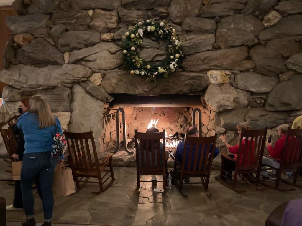 Guests in rocking chairs by the great stone fireplace in the Grove Park Inn Great Hall