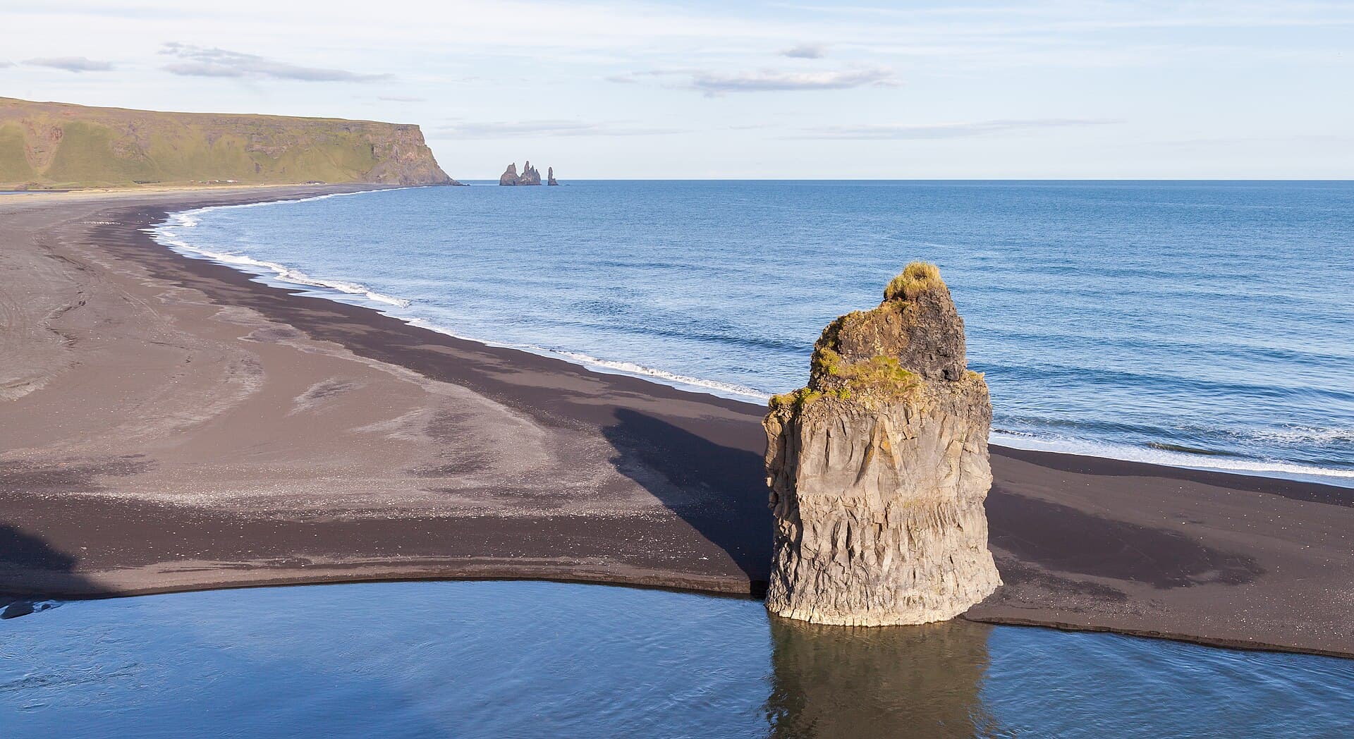 Basalt sea stack on the black sand beach at Reynisfjara with the Reynisdrangar beyond
